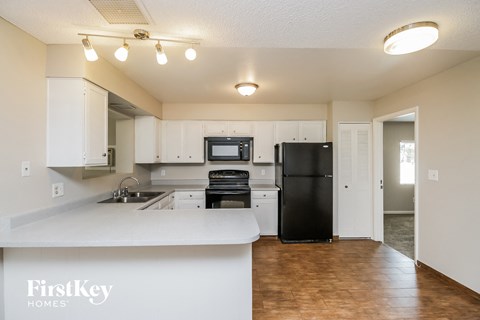 A kitchen with a black refrigerator and white cabinets.
