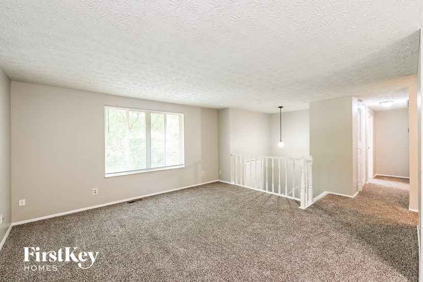 an empty living room with carpet and a white staircase