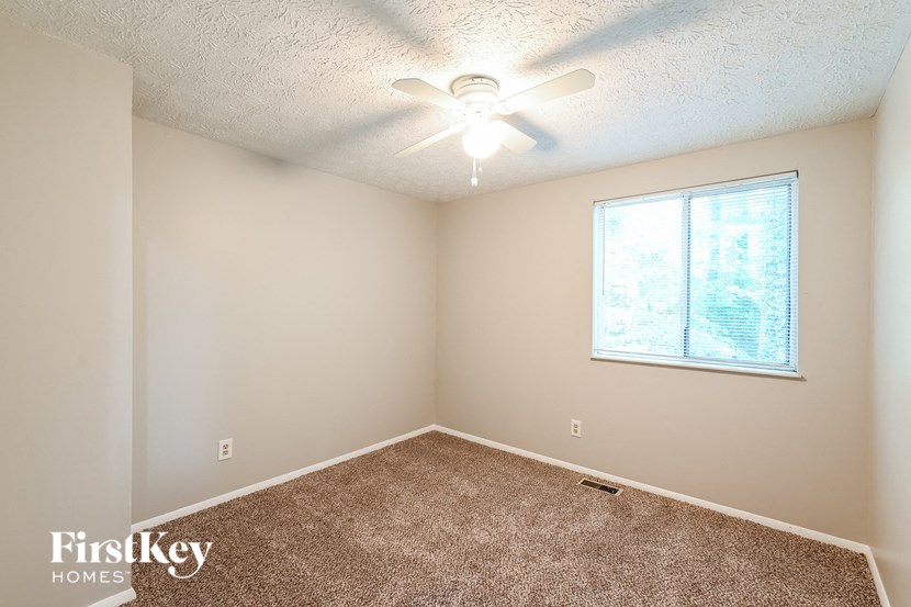 an empty room with a ceiling fan and a window