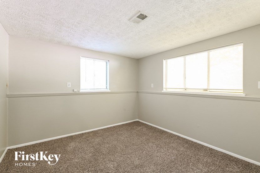an empty room with two windows and a carpet