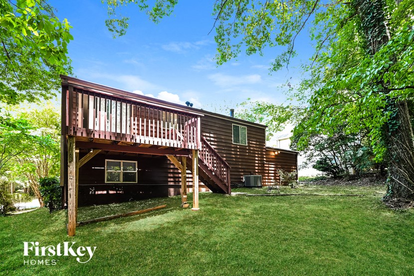 the back of the cabin with a deck and a lawn