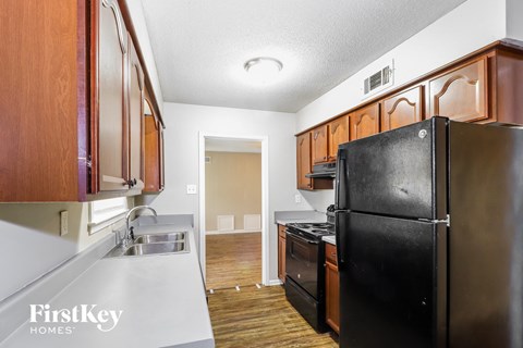 A kitchen with wooden cabinets and a black fridge.