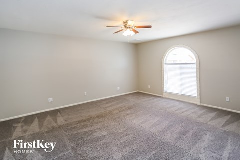 A room with a carpeted floor and a ceiling fan.