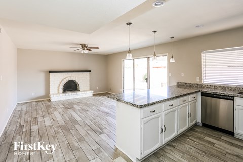 A spacious kitchen and living room with a fireplace and a ceiling fan.