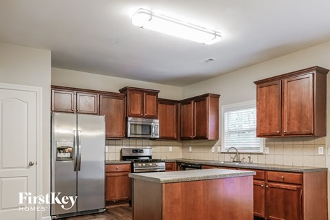A kitchen with wooden cabinets and a stainless steel refrigerator.