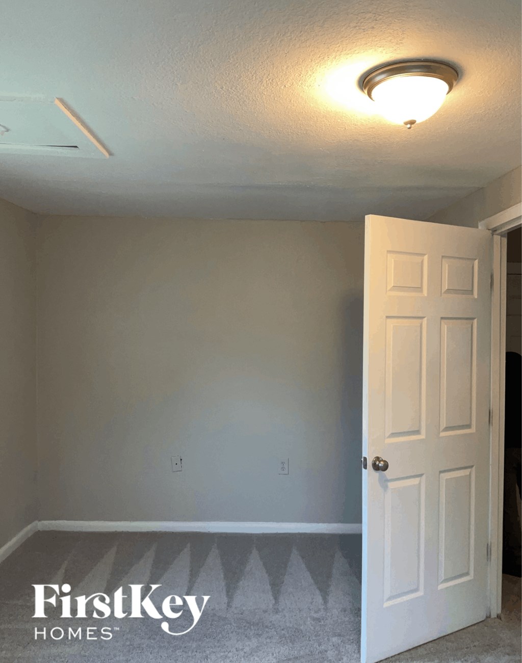 an empty room with a white door and a light on the ceiling