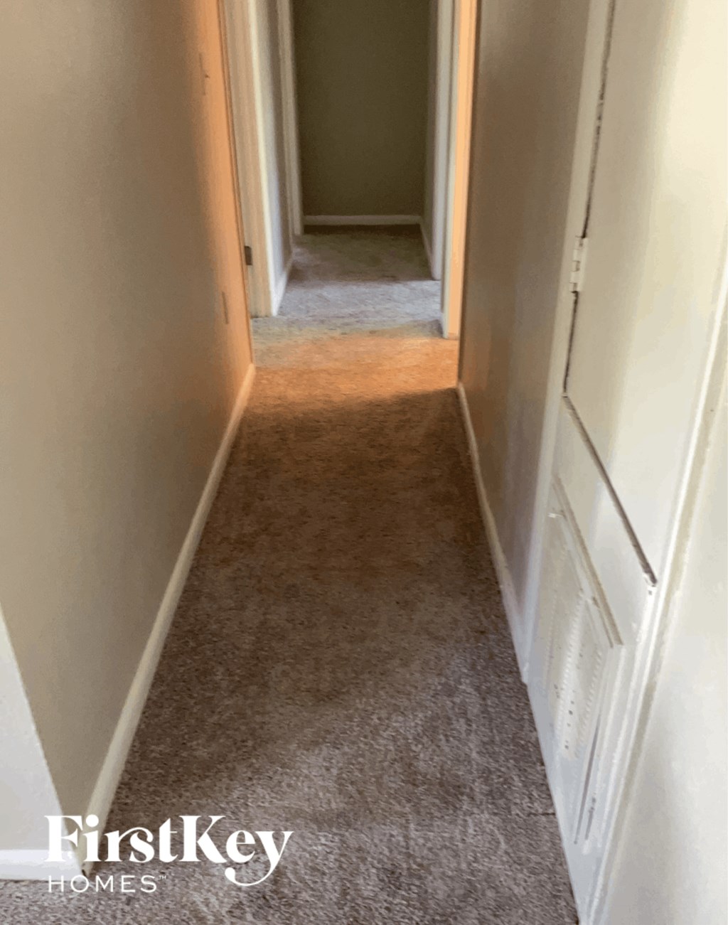 a hallway with a carpeted floor and a door to a closet