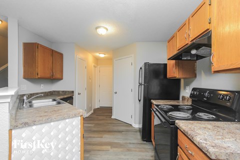 A kitchen with a black fridge and stove top oven.