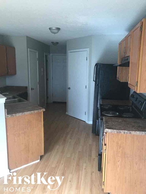 A kitchen with wooden cabinets and a black fridge.
