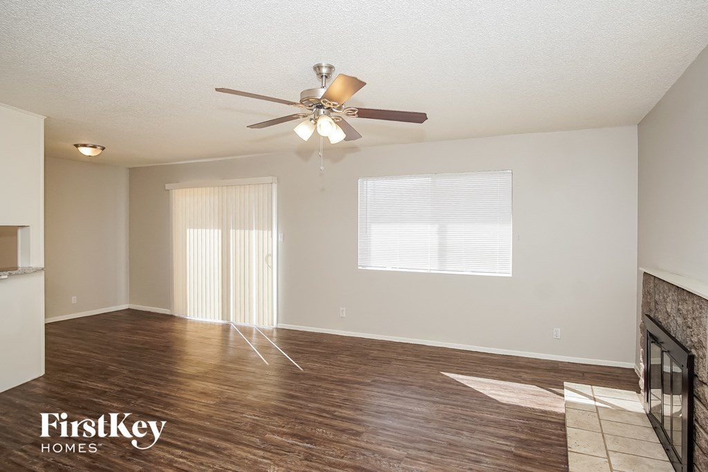 the spacious living room with hardwood flooring and a ceiling fan
