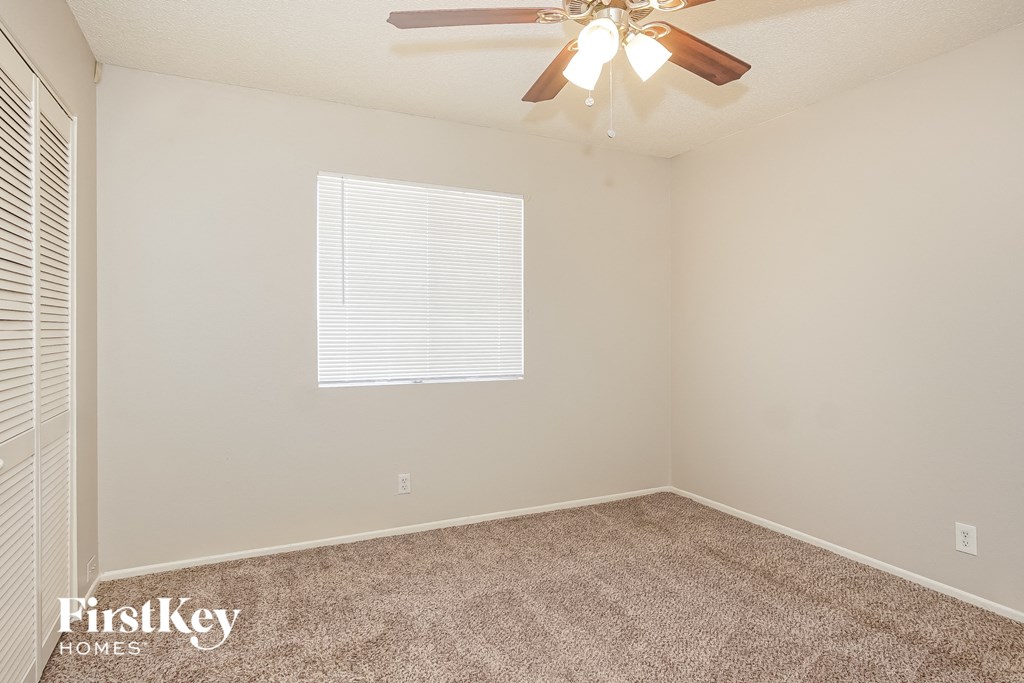 the spacious bedroom has carpeted floors and a ceiling fan