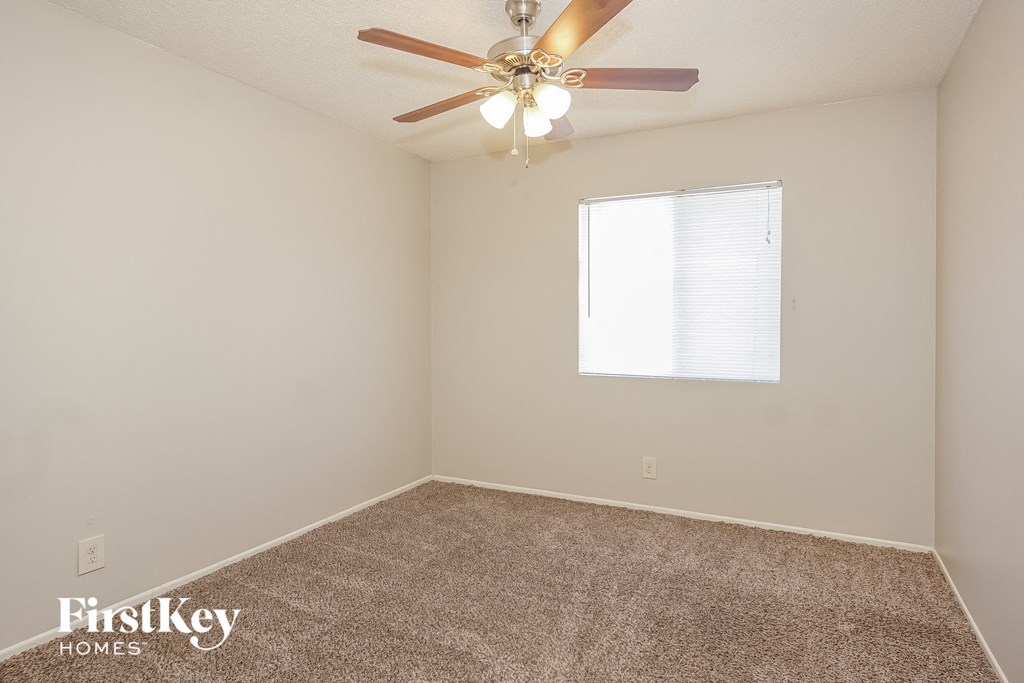 the spacious living room of an empty house with a ceiling fan