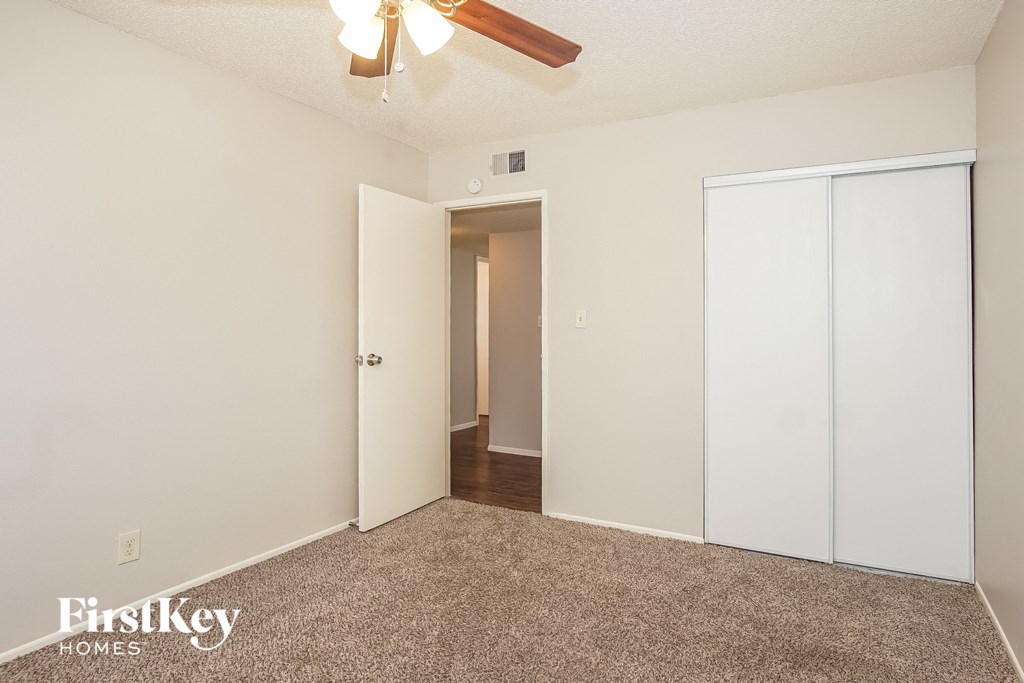 the living room of an apartment with white walls and a ceiling fan