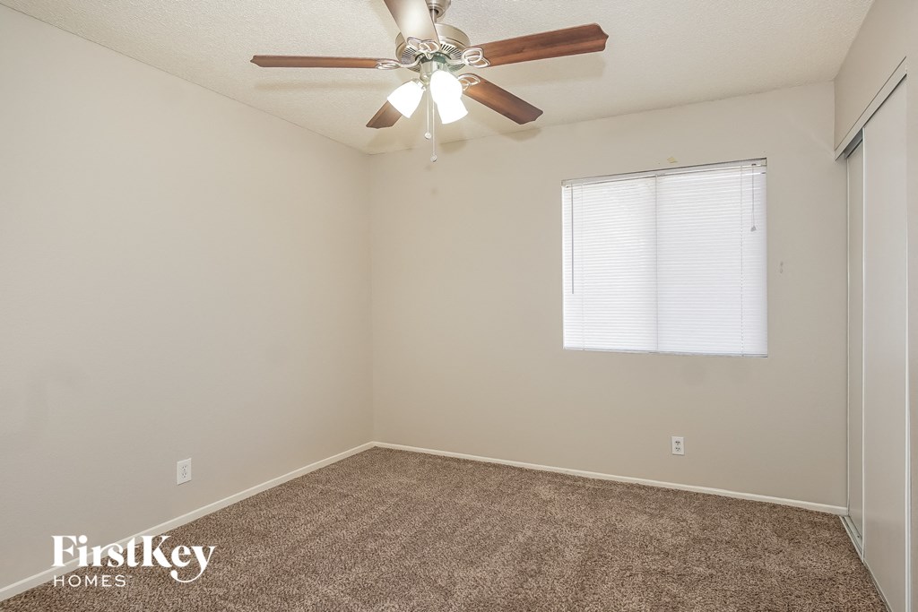 the spacious living room with ceiling fan and carpet