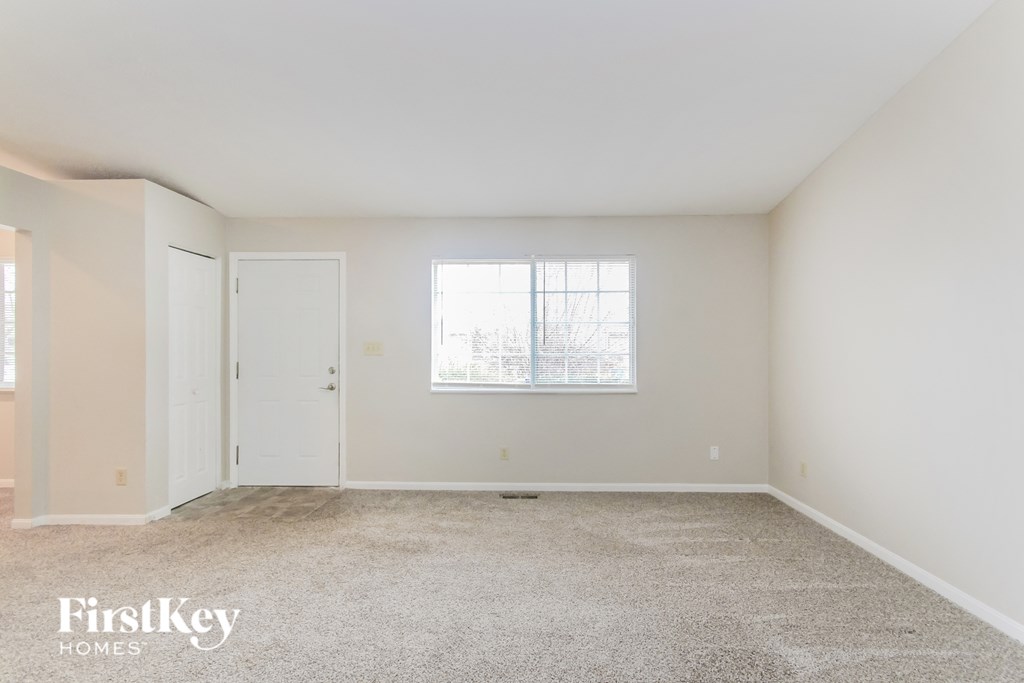 a bedroom with white walls and carpet and a window