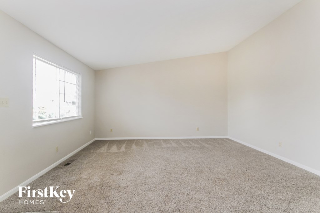 a spacious room with carpet and a window