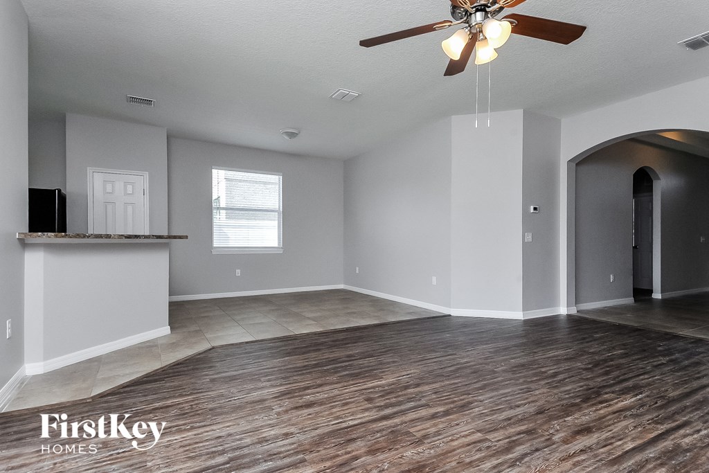the living room and dining room of an empty house with a ceiling fan