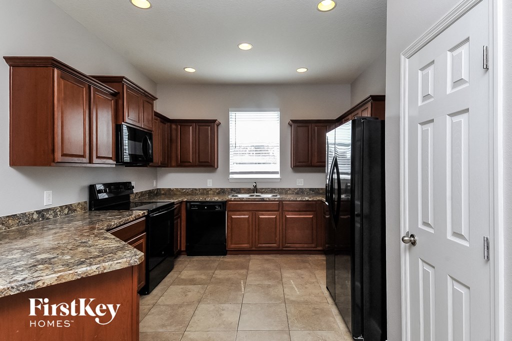 a kitchen with wooden cabinets and granite counter tops and a black refrigerator