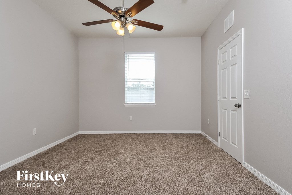 the master bedroom has a ceiling fan and carpet
