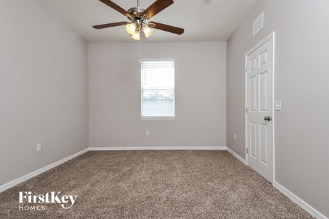 the master bedroom has a ceiling fan and carpet