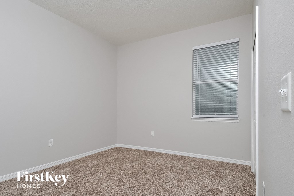 a bedroom with a window and a carpeted floor