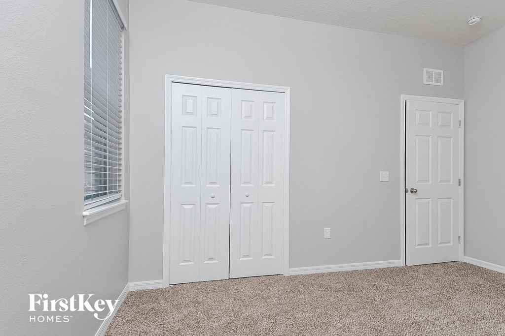 a bedroom with two closets and a door and a window