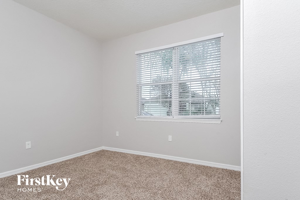 a bedroom with a window and a carpeted floor