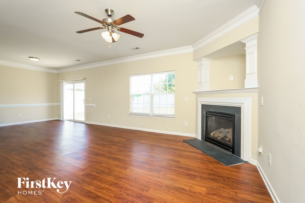 A spacious living room with a fireplace and a ceiling fan.