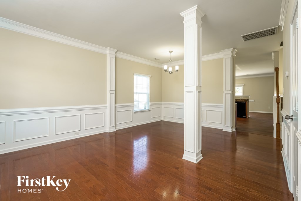 A large empty room with wooden floors and white columns.