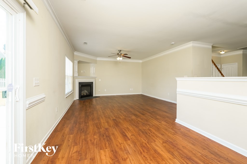 A large empty room with wooden floors and a fireplace.