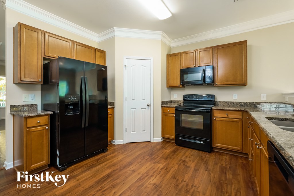 A kitchen with wooden cabinets and a black refrigerator.