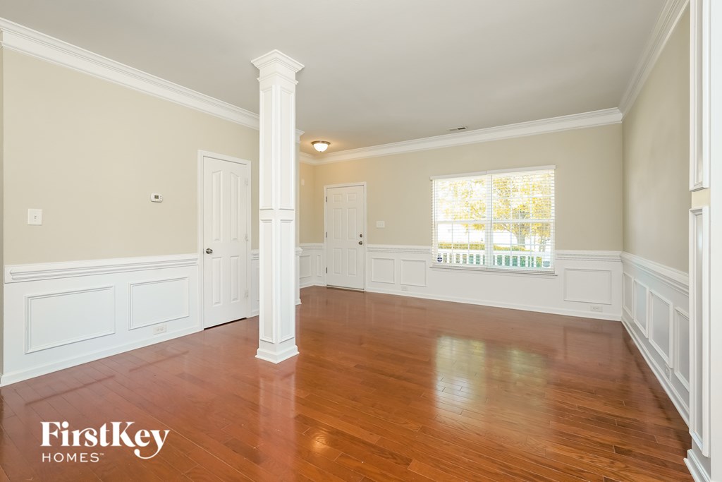 A spacious room with wooden floors and white trim.