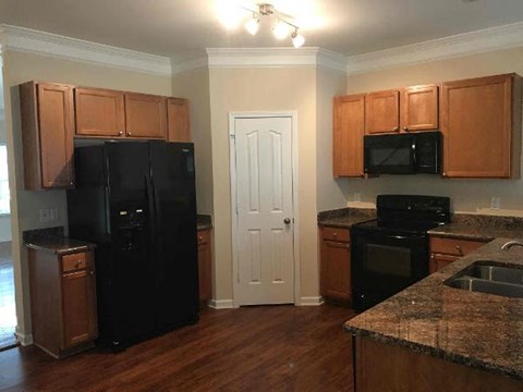 A kitchen with black appliances and wooden cabinets.