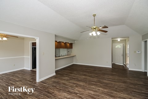an empty living room with a ceiling fan and a kitchen
