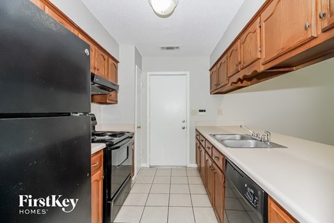 a kitchen with wood cabinets and white counter tops and black appliances