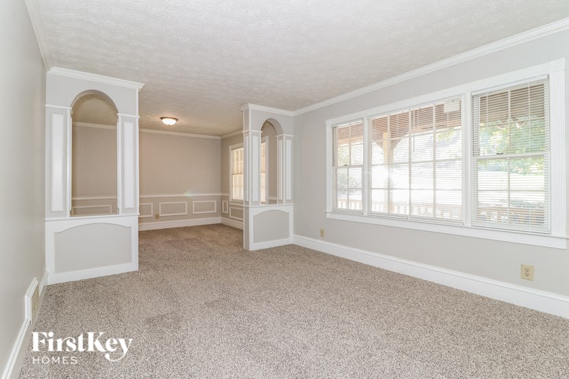 an empty dining room with white pillars and a window