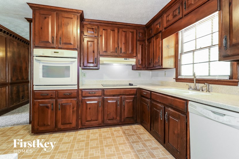 a kitchen with wooden cabinets and white appliances and a window