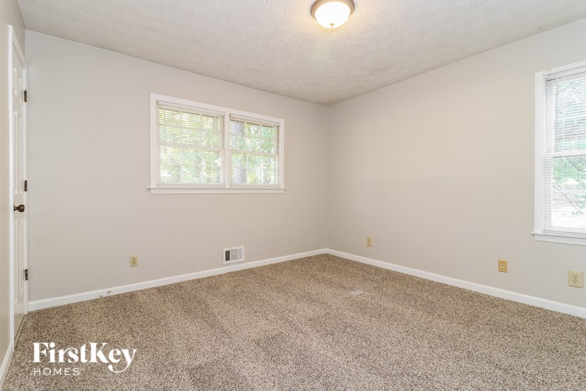 a bedroom with a carpeted floor and two windows
