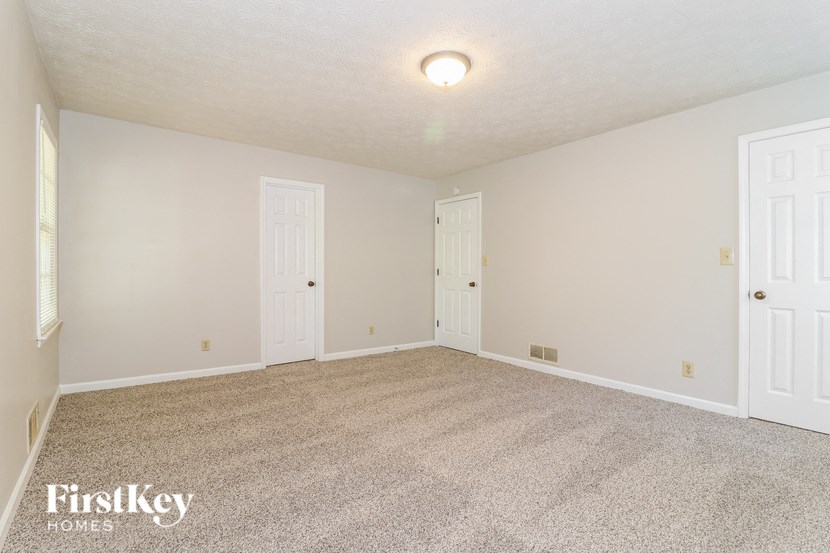 a spacious living room with carpet and two doors