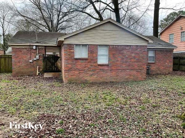 a small brick house in the middle of a yard