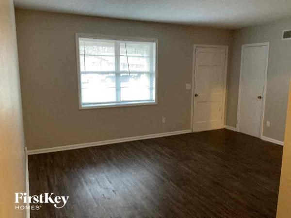 an empty living room with wood floors and a window