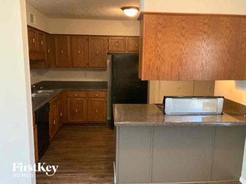 A kitchen with wooden cabinets and a black refrigerator.