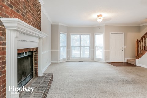 a living room with a brick fireplace and a carpeted floor