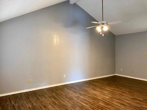 a living room with wood floors and a ceiling fan