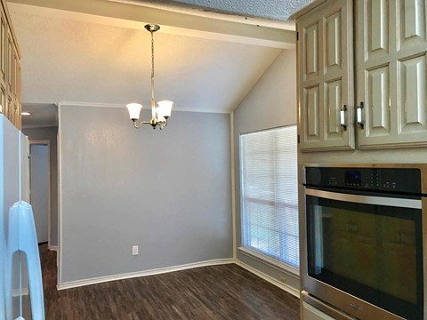 a kitchen with a stove and a microwave and a wall with white cabinets