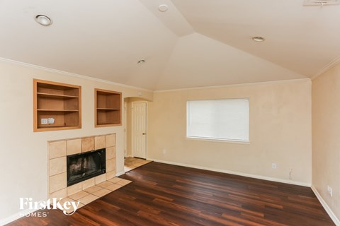 A living room with a fireplace and wooden floors.