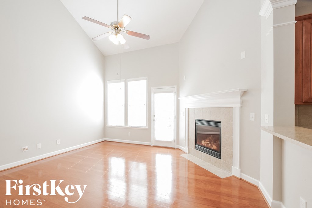 an empty living room with a fireplace and a ceiling fan