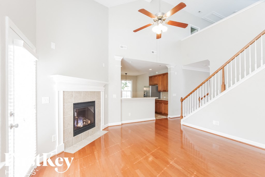an empty living room with a fireplace and a ceiling fan