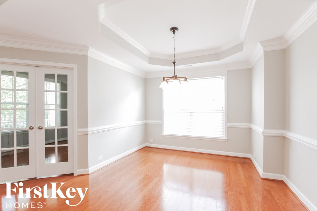 an empty dining room with white walls and a wood floor