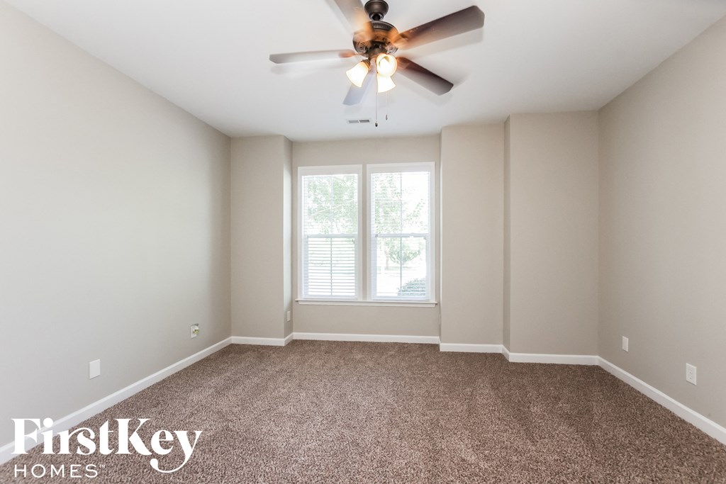 an empty room with a ceiling fan and a window